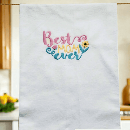 Best Mom Ever Towel - Embroidered Gift | Flour Sack 27"x27" hanging in a cozy kitchen, showcasing colorful embroidery for Mother's Day or birthdays.