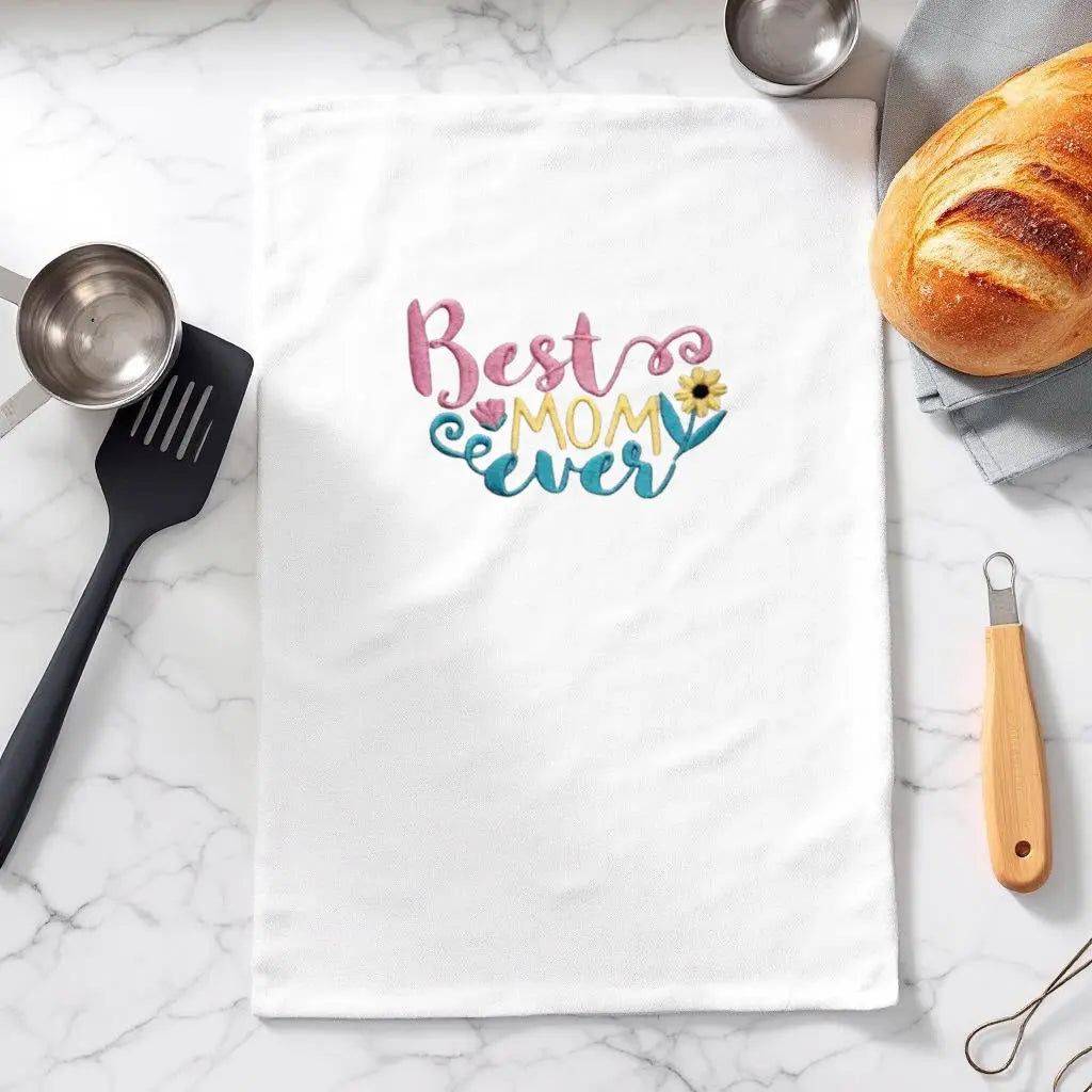 Best Mom Ever Towel - Embroidered Gift | Flour Sack 27"x27" displayed on a marble kitchen counter with utensils and bread, ideal for gifting.