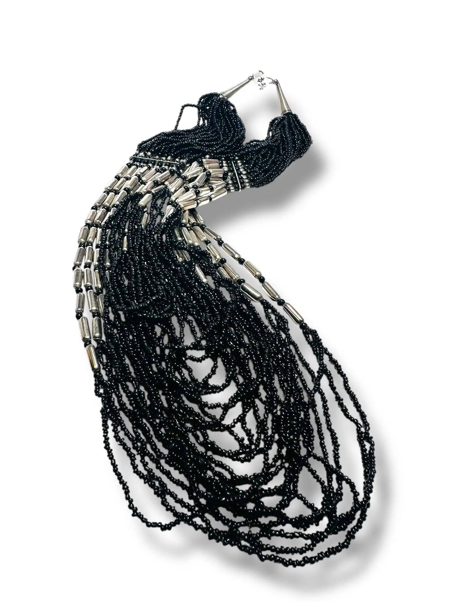 Black beaded necklace with cascading strands and silver accents laid flat, highlighting its intricate design and adjustable 20–32 inch length.