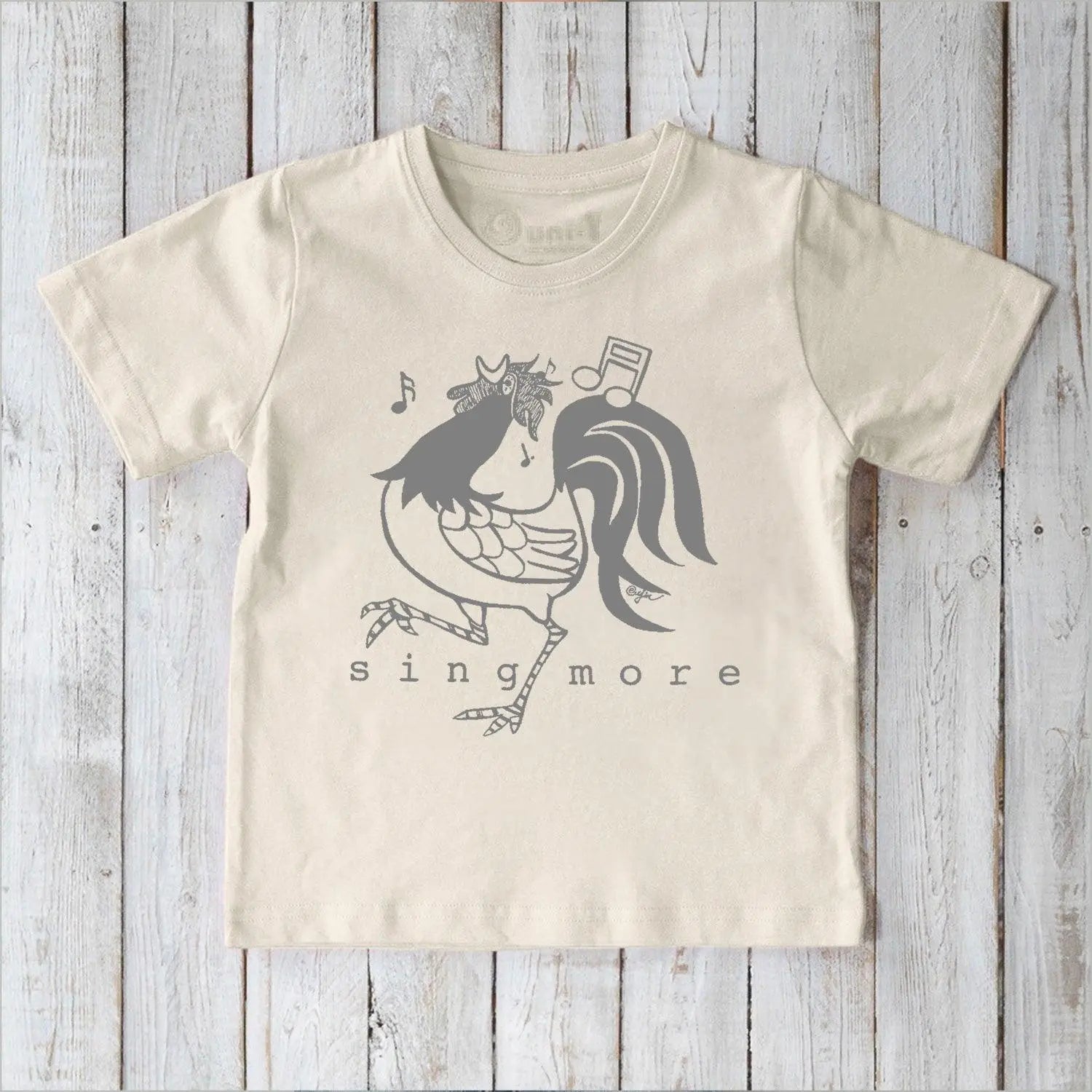 Eco-friendly kids' rooster graphic tee in cream, organic cotton shirt with 'Sing More' text, perfect for sensitive skin.