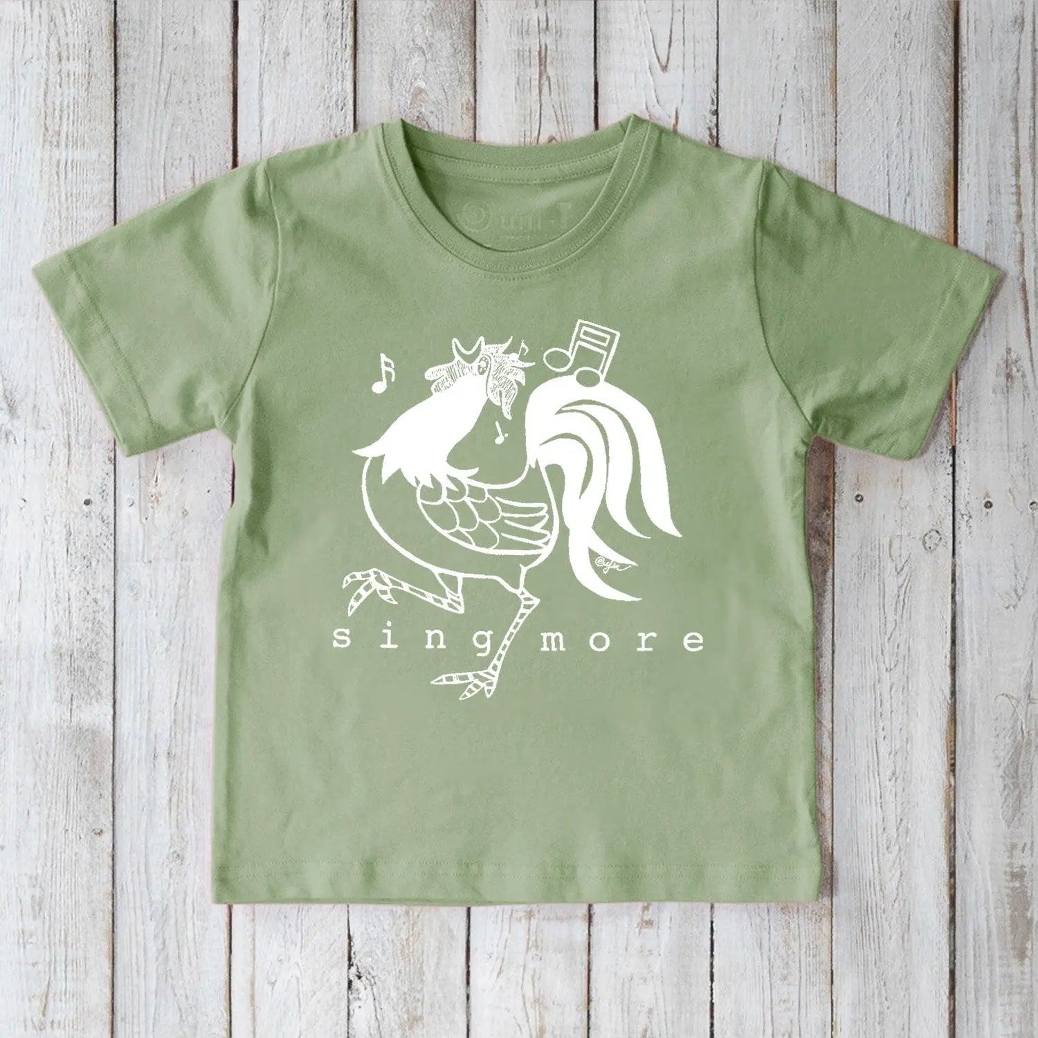 Green organic cotton kids' t-shirt featuring a fun rooster and 'Sing More' design, sustainable and playful farm-themed apparel.