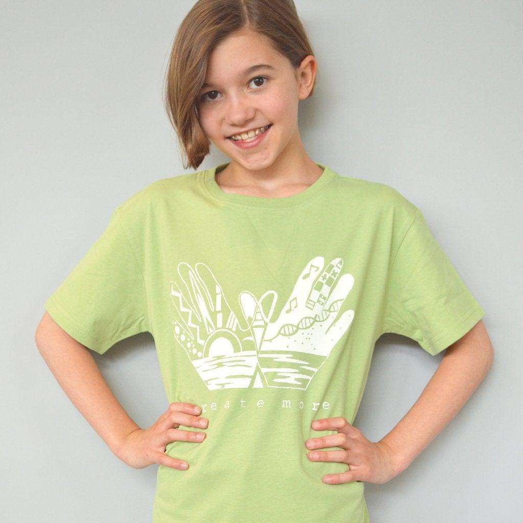 Child wearing light green Kids' Creative Art Organic Cotton T-Shirt with 'Create More' hand graphic, eco-friendly and inspirational top by Uni-T.