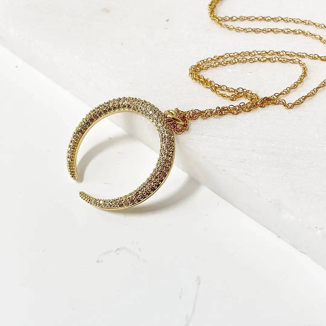 Close-up of gold crescent moon pendant encrusted with cubic zirconia on a dainty 18” rope chain. Perfect accessory for minimalist style.