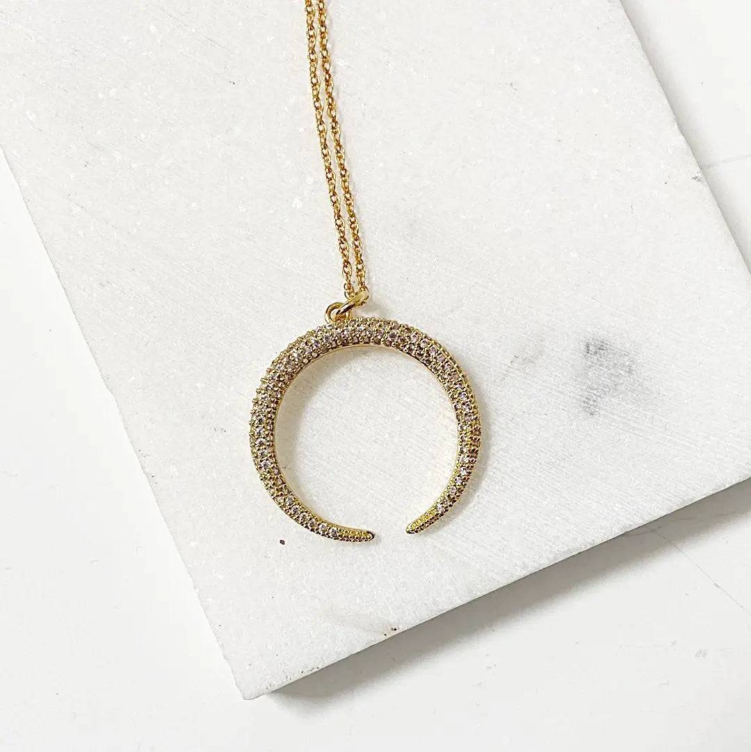 Minimalist gold crescent moon pendant with cubic zirconia detailing, hanging from an 18” rope chain, styled for elegant solo wear.