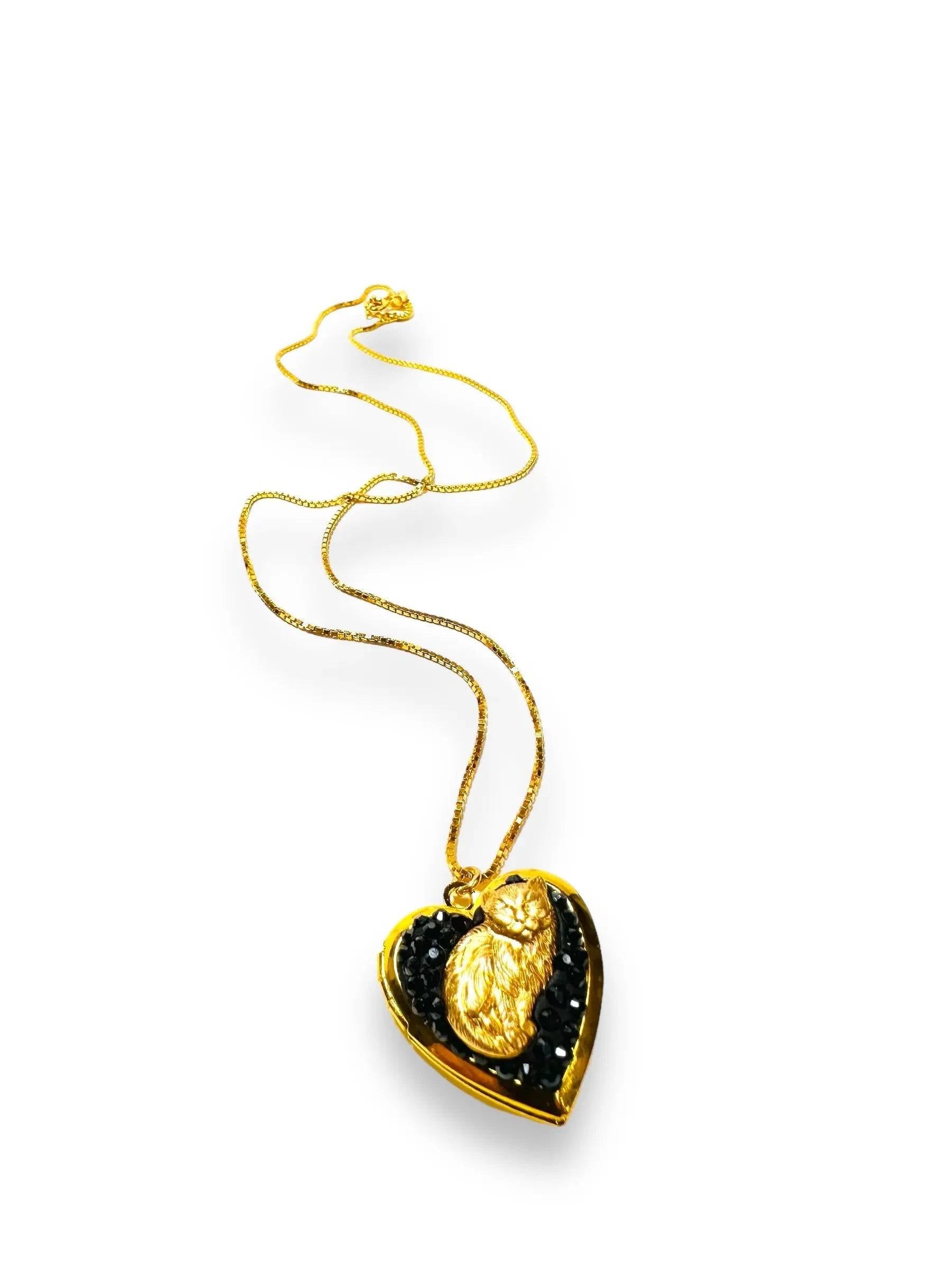 Heart-shaped brass locket featuring a sculpted gold cat and black crystal clay inlay, a charming accessory for cat lovers.