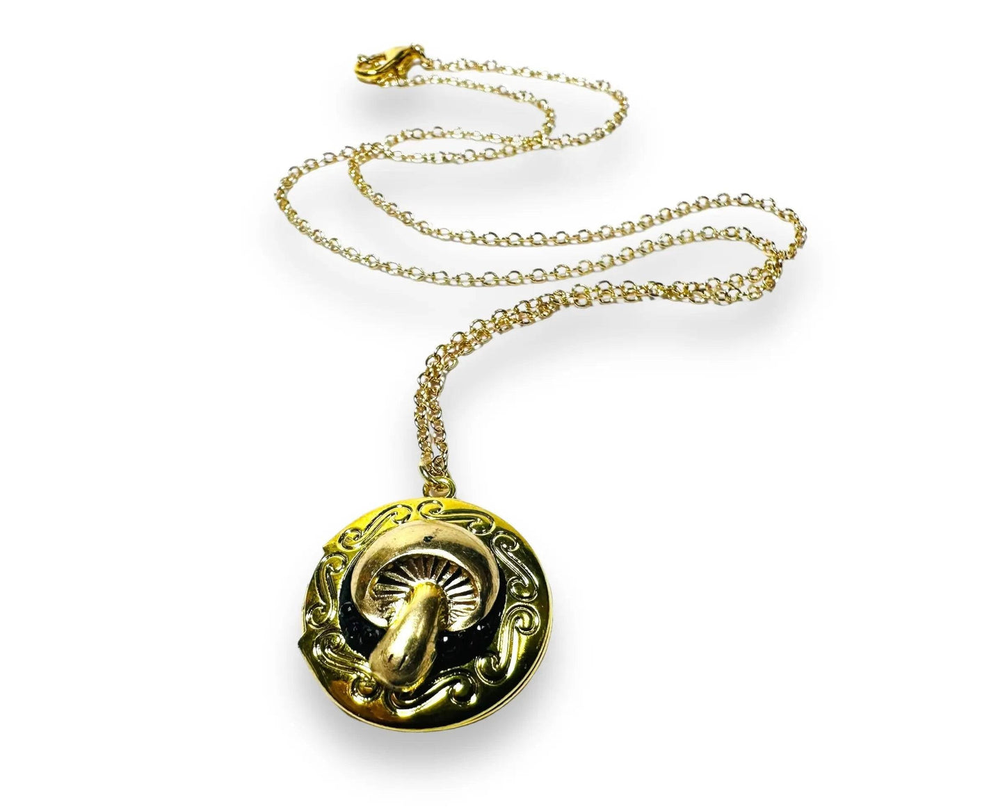 Round brass locket with ornate mushroom design and black crystal clay inlay, a whimsical and affordable gift option.