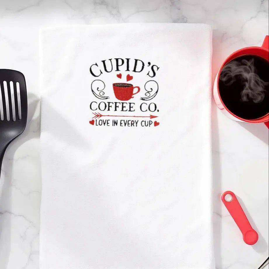 Cupid's Coffee Co. Towel - Embroidered Kitchen Towel displayed on marble countertop with coffee and utensils, ideal for gifting and decor.