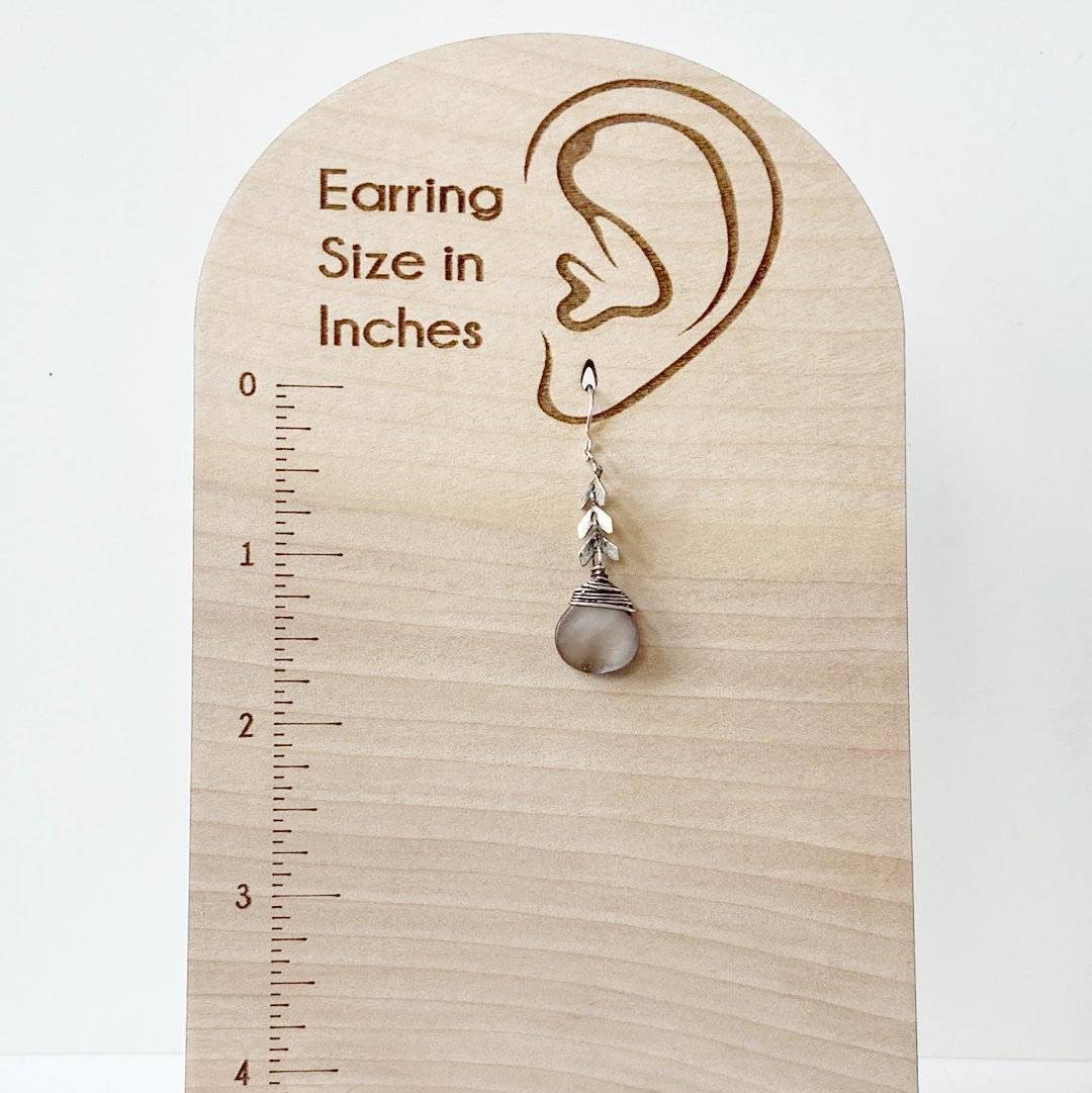 Abalone Chevron Earring shown on a wooden earring size chart, illustrating its drop length and elegant sterling silver and brass craftsmanship.