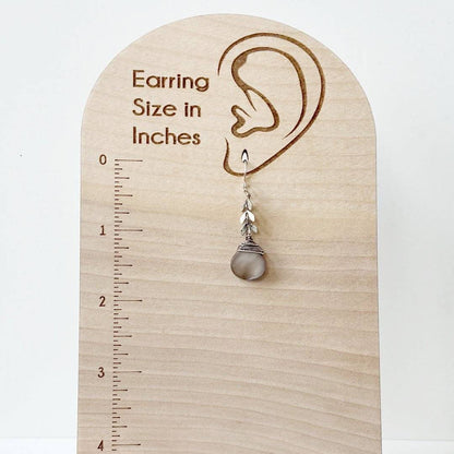 Abalone Chevron Earring shown on a wooden earring size chart, illustrating its drop length and elegant sterling silver and brass craftsmanship.