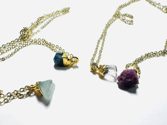 Raw gemstone necklaces with aquamarine, sapphire, Herkimer diamond, and ruby pendants on gold brass chains. Affordable gifts by UNI-T Jewelry.