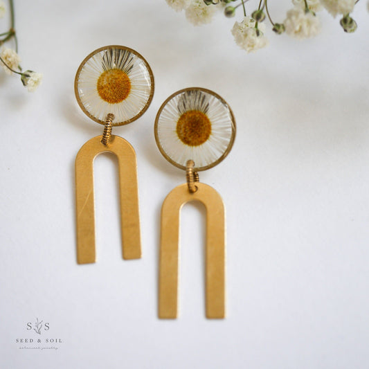 Daisy Chime Earrings - Hope Symbol Jewelry featuring real pressed daisies in resin with gold-tone wind chime arches. Elegant handmade earrings.