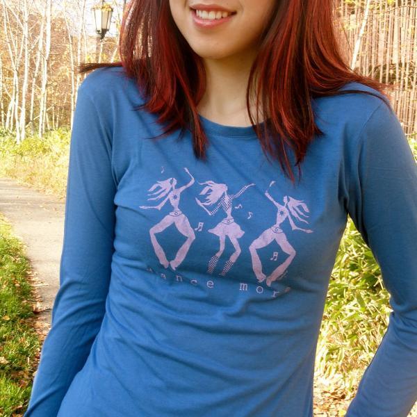 Smiling woman in blue Women's Dance More Long Sleeve T-Shirt with pink dancer design, ideal for dancers and fitness enthusiasts.
