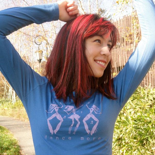 Happy woman stretching in blue Women's Dance More Long Sleeve T-Shirt with pink dancer graphic, made from soft bamboo and organic cotton.