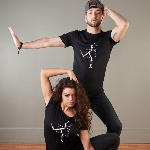 Couple wearing matching 'Dancing Outside the Box' graphic tees in black, showcasing the men's bamboo and organic cotton t-shirt in a dance pose.