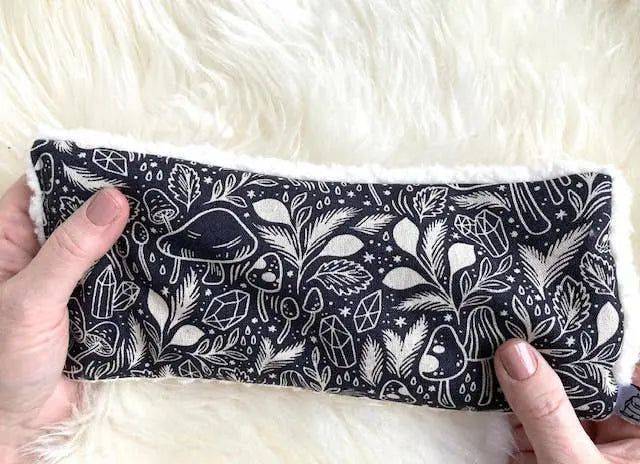 Hands holding Deep Rest Eye Pillow - Forest Forage with detailed forest-themed pattern, perfect for acupressure and soothing tired eyes.