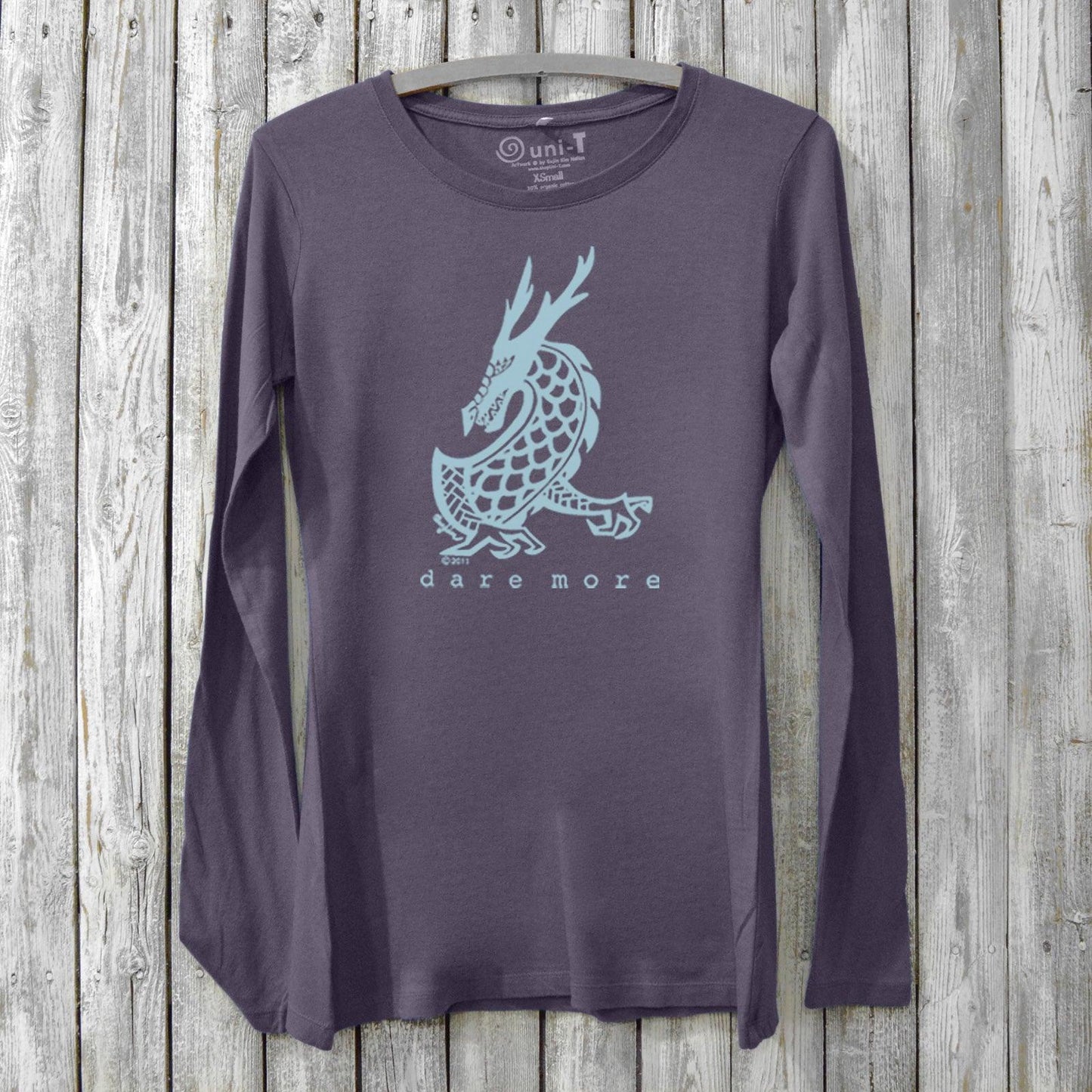 Dark purple women's long sleeve graphic tee in bamboo and organic cotton with light blue dragon and 'Dare More' print. Mythical design for bold living.