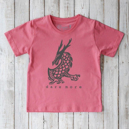 Coral pink Kids' Organic Cotton T-Shirt with black dragon design and 'dare more' print. Sustainable fantasy-themed top by Uni-T.