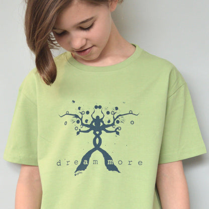Child wearing green Kids' Organic Cotton T-Shirt with blue 'Dream More' graphic. Eco-friendly inspirational top by Uni-T for children.