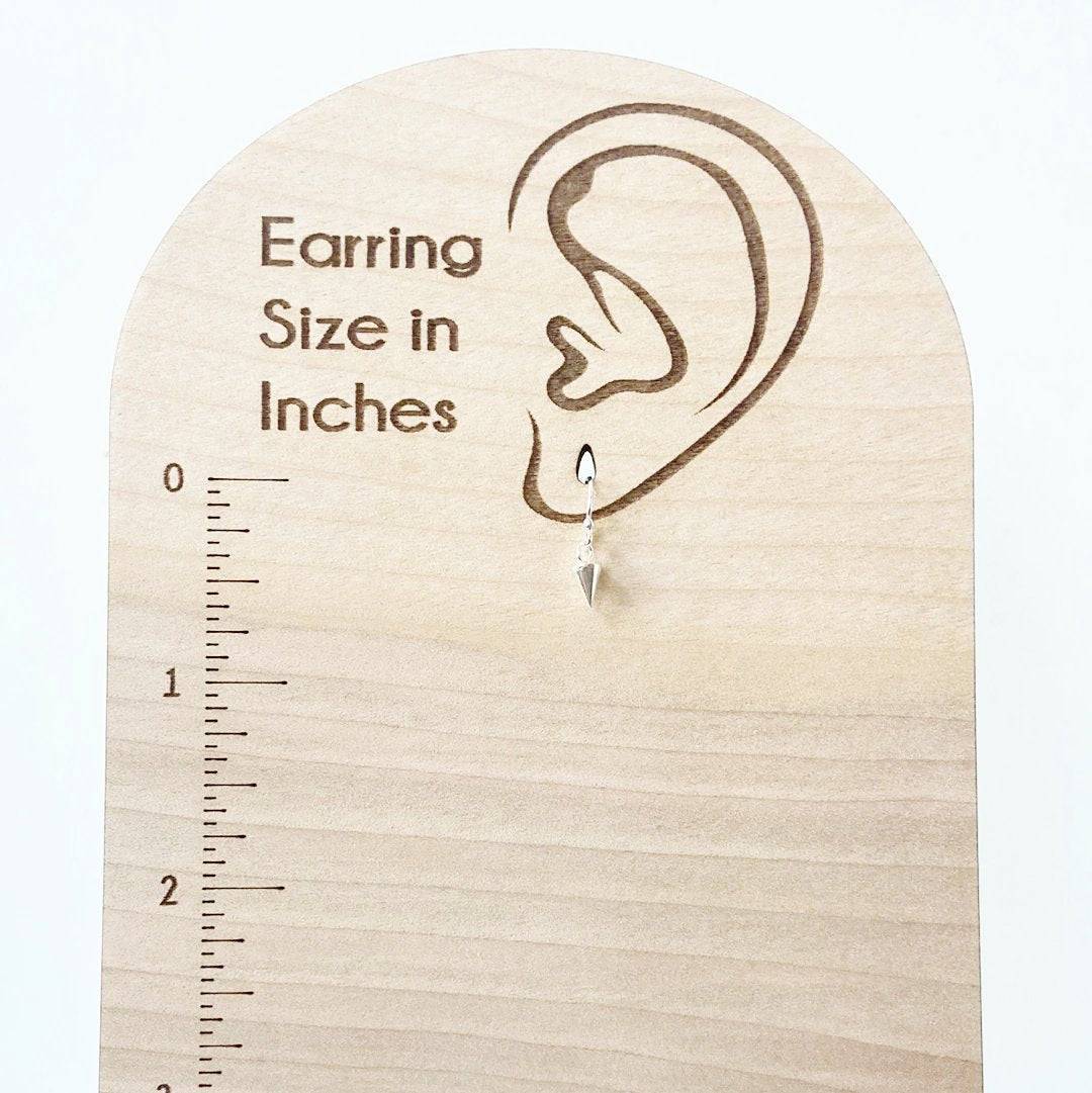 Tiny Spike Earrings-Uni-T - Sterling Silver hanging on a wooden size chart, measuring under 1 inch for a subtle yet bold fashion statement.