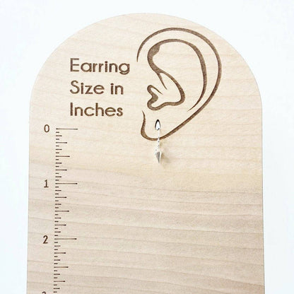 Tiny Spike Earrings-Uni-T - Sterling Silver hanging on a wooden size chart, measuring under 1 inch for a subtle yet bold fashion statement.