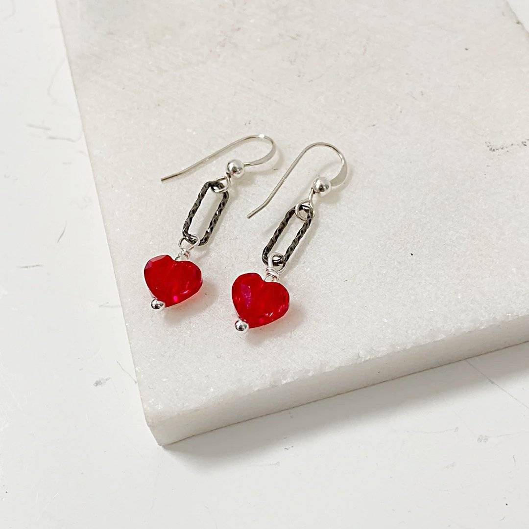 Red Heart Earrings - Standout Jewelry with Red Crystals shown in close-up with textured silver links and dangling red heart-shaped beads.