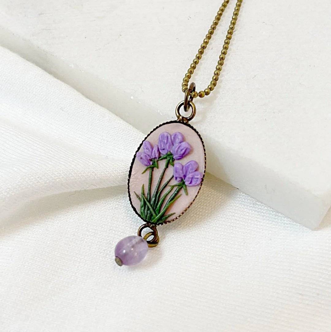 Side view of Uni-T Polymer Clay Floral Necklace with purple floral motif on blush pink pendant and matching lavender gemstone bead.
