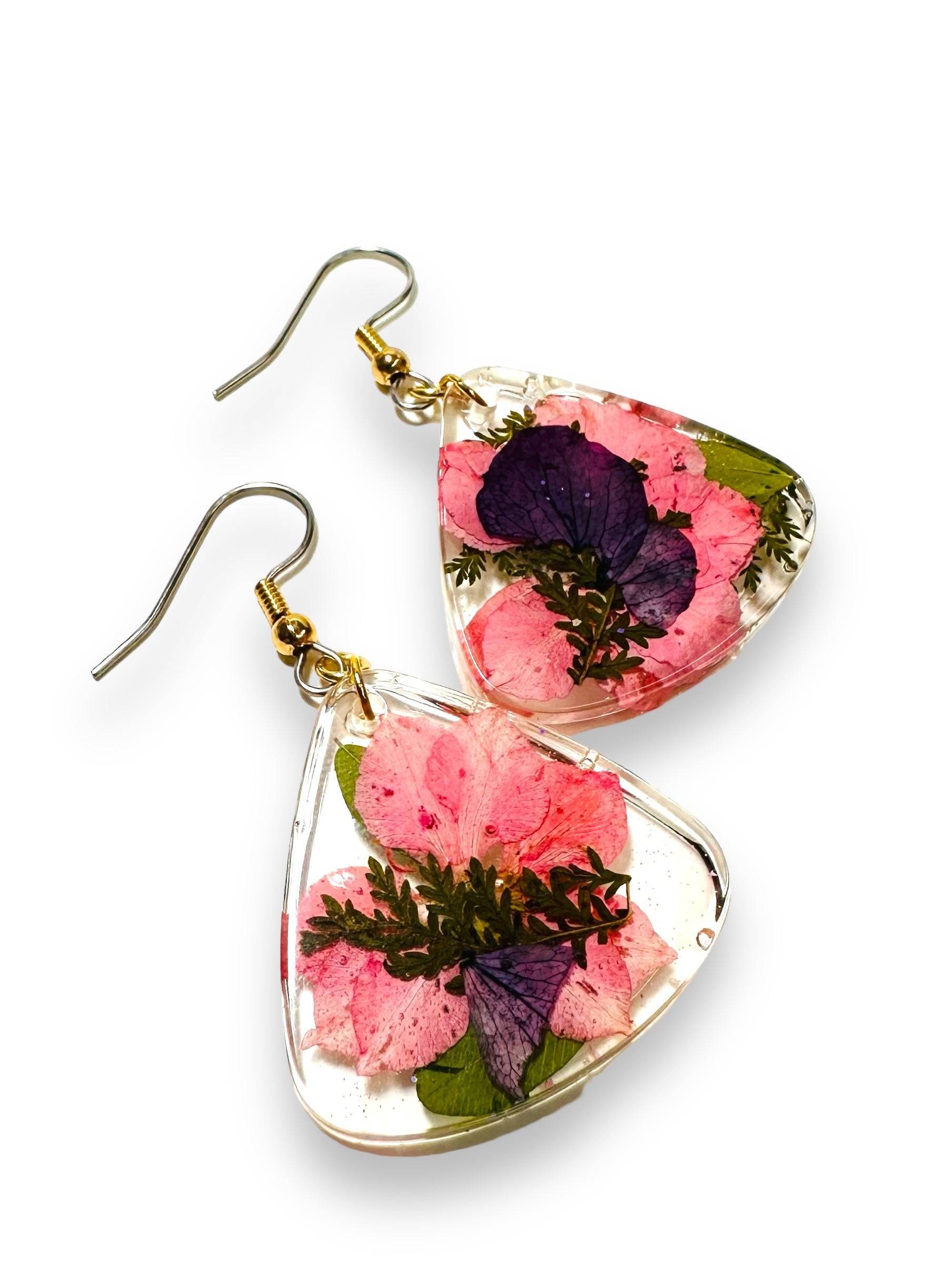 Triangle resin earrings with pink and purple flowers and gold hooks. Nature-inspired real flower earrings with a soft color palette.