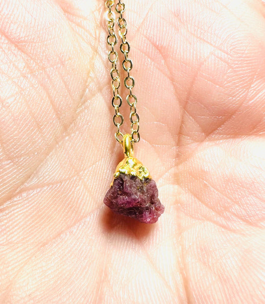 Close-up of raw ruby gemstone necklace with gold-dipped top on a brass chain. Dainty and mystical gift from UNI-T Jewelry.