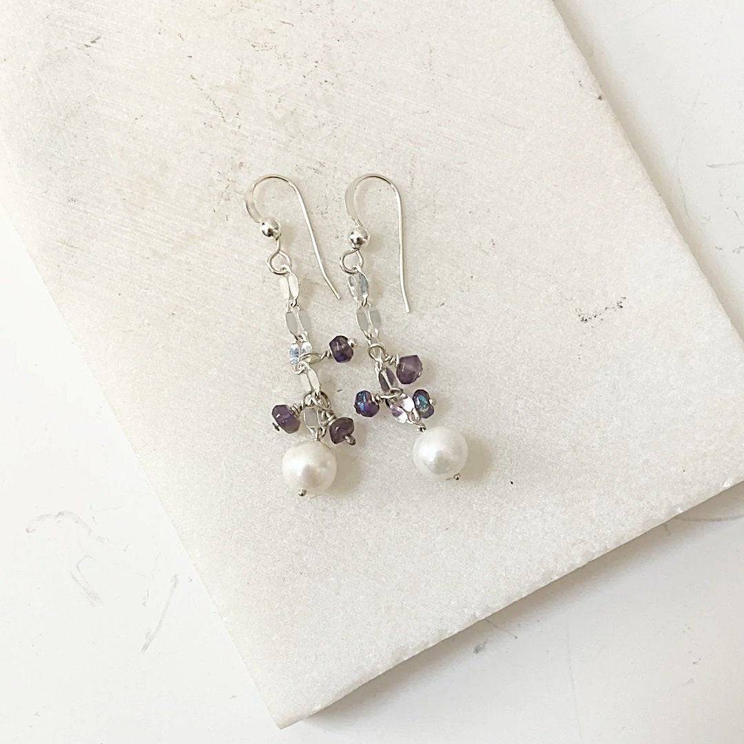 Cultured Pearl Earrings - Amethyst | Sterling Silver displayed on a white marble surface, featuring dangling pearls and purple amethyst beads.