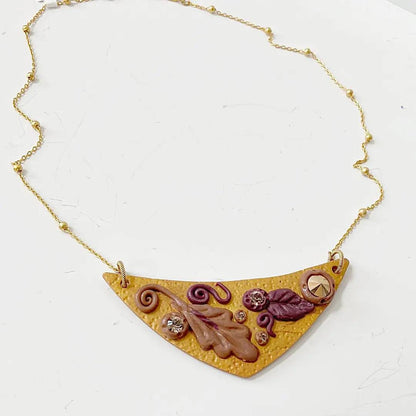 Polymer clay Fall Leaves Bib Necklace with sculpted leaf motifs and embedded crystals on a gold-plated chain. Elegant fall statement necklace.