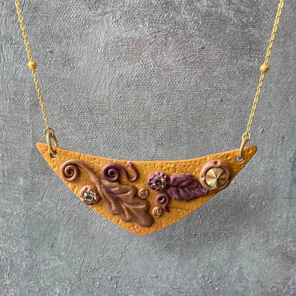 Fall Leaves Bib Necklace with earthy-toned polymer clay pendant, crystal embellishments, and gold-plated chain. Perfect for seasonal fashion.