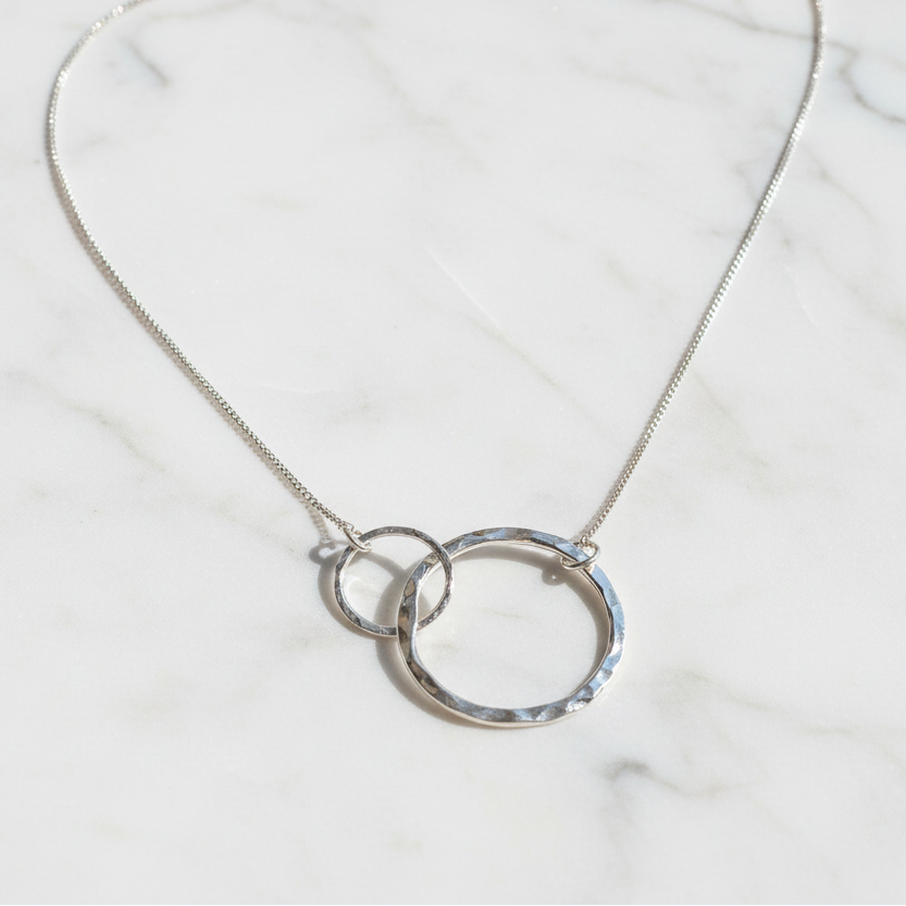 Silver necklace with interlocking rings on a textured surface