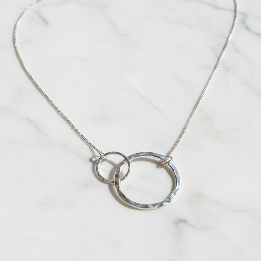 Silver necklace with interlocking rings on a textured surface