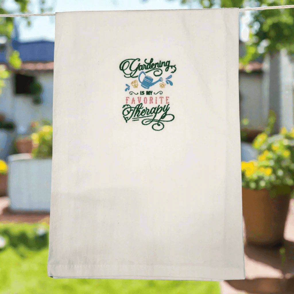 Embroidered Gardening Is My Favorite Therapy Towel hanging outdoors, perfect kitchen towel gift for gardening enthusiasts.