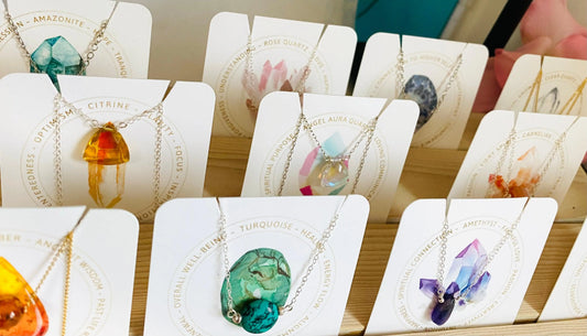 Handmade gemstone necklace assortment displayed on cards with crystal meanings, featuring amethyst, citrine, turquoise, and more.