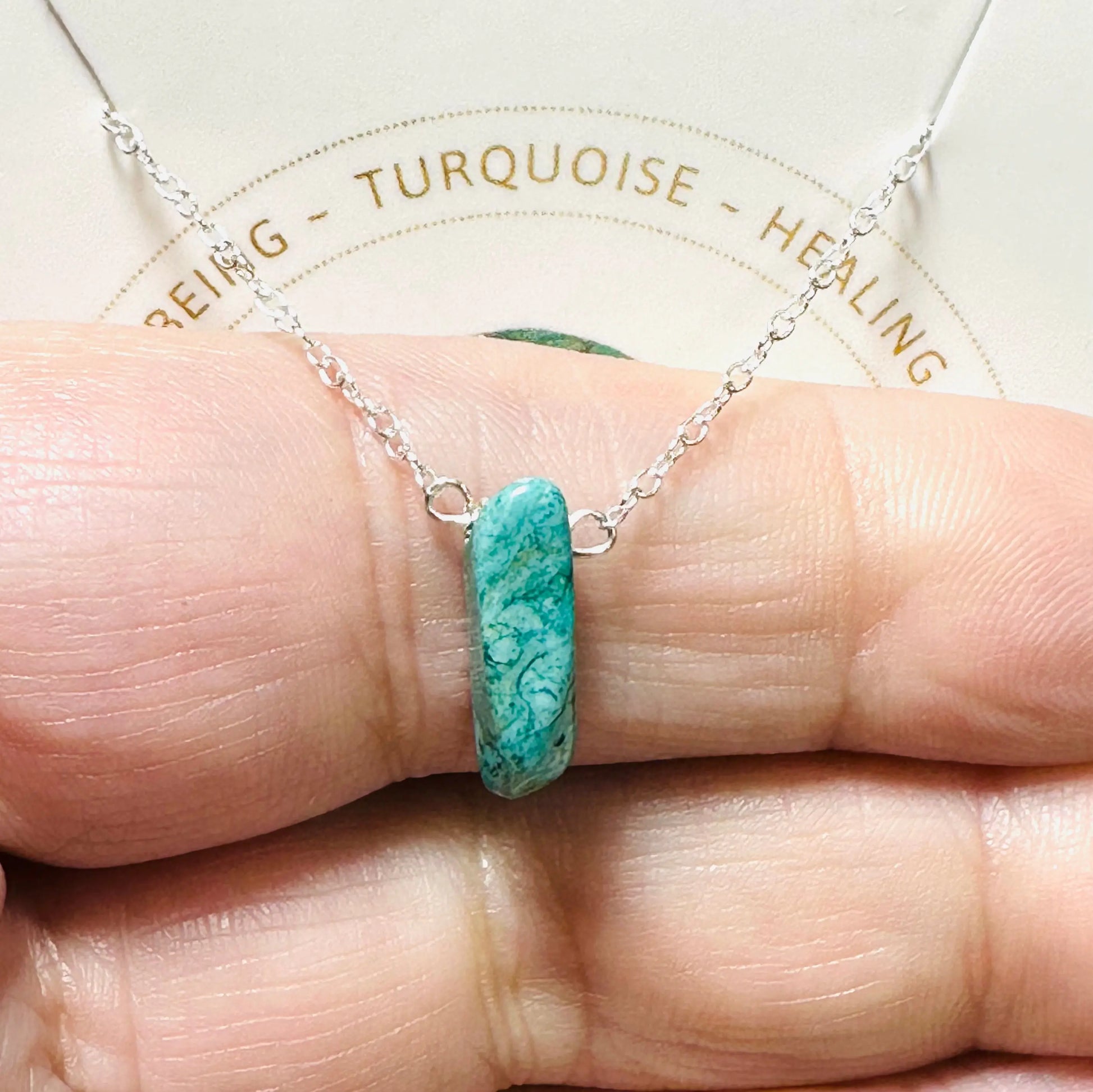 Turquoise bar pendant necklace held in hand, representing healing and overall well-being, on sterling silver chain.