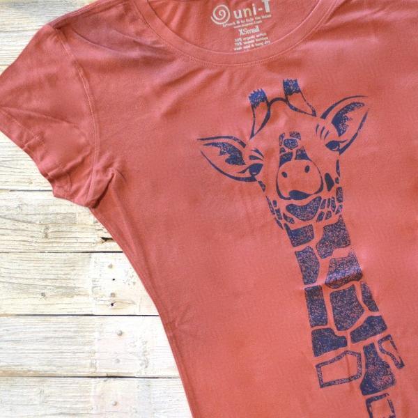 Rust red Women's Giraffe T-Shirt with blue ink animal print. Eco-friendly bamboo and organic cotton tee for casual safari-inspired fashion.