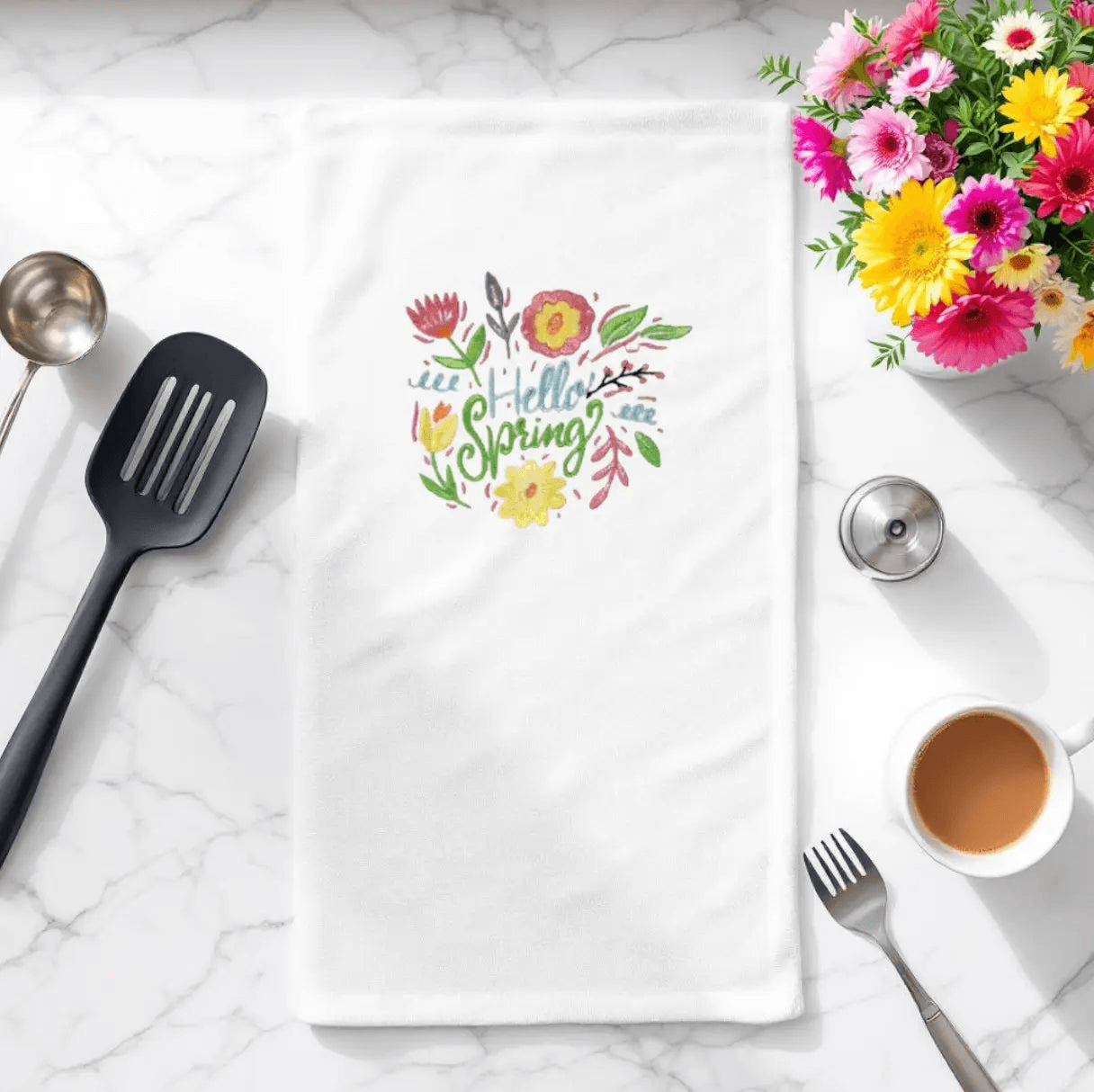 Embroidered towel with 'Hello Spring' floral design displayed on kitchen counter. Perfect spring flowers towel for seasonal kitchen decor.