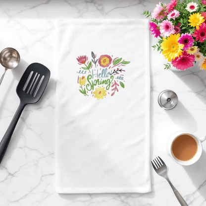 Embroidered towel with 'Hello Spring' floral design displayed on kitchen counter. Perfect spring flowers towel for seasonal kitchen decor.