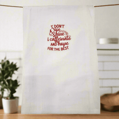 White embroidered kitchen towel hanging with red coffee-themed quote, perfect small gift for morning routines and caffeine enthusiasts.