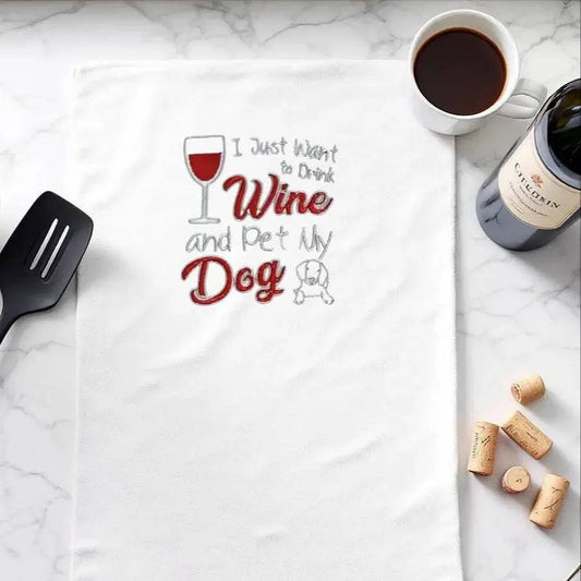Wine Dog Embroidered Towel on marble counter with wine, coffee, and corks; quirky kitchen essential for dog and wine lovers.