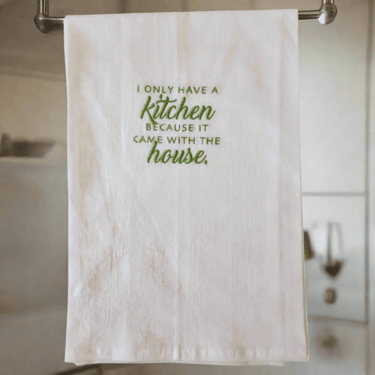 Flour sack embroidered kitchen towel hanging in a modern kitchen, featuring funny green text for a playful home decor touch.