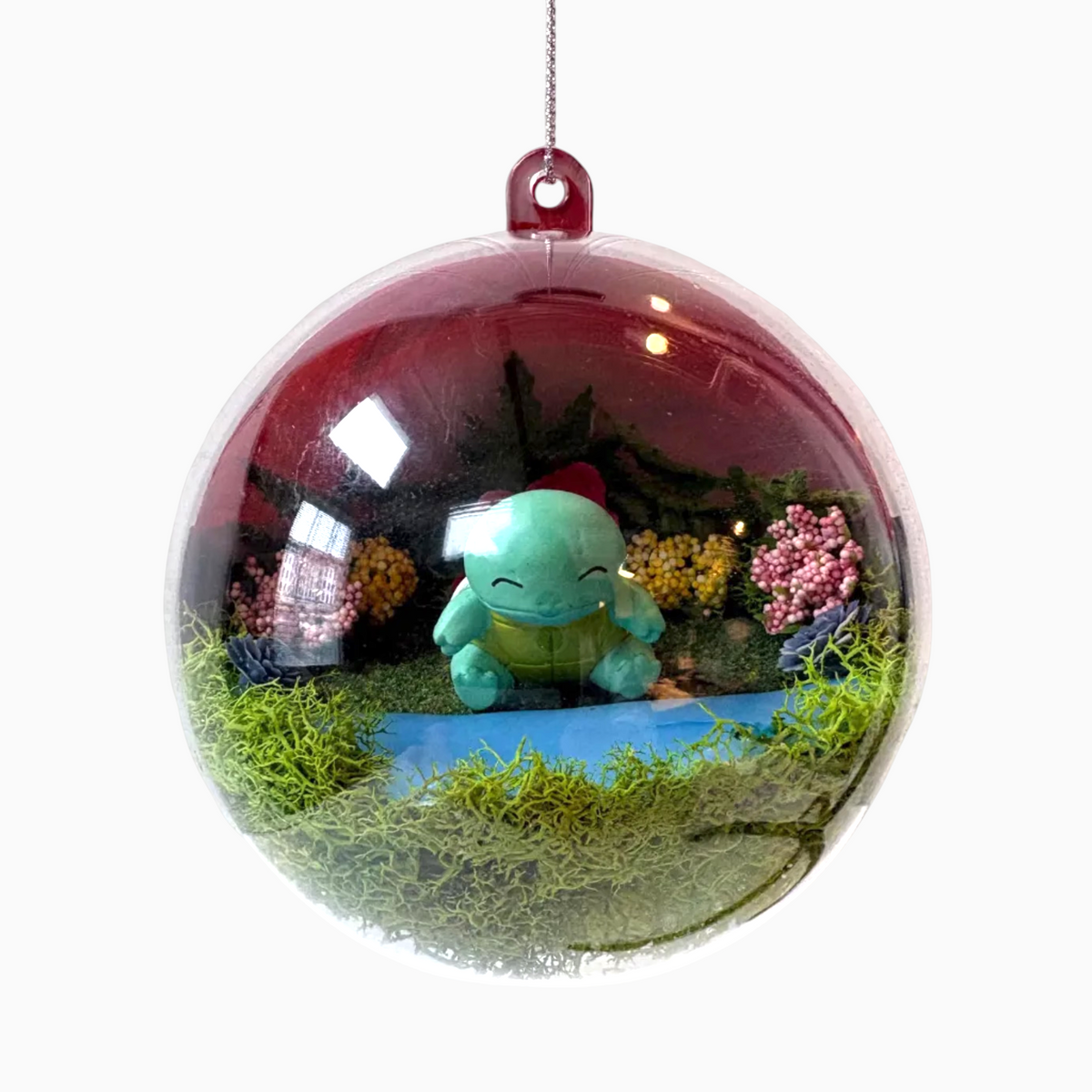 Uni-T Pokeball terrarium ornament featuring a Squirtle figure surrounded by moss and miniature flowers