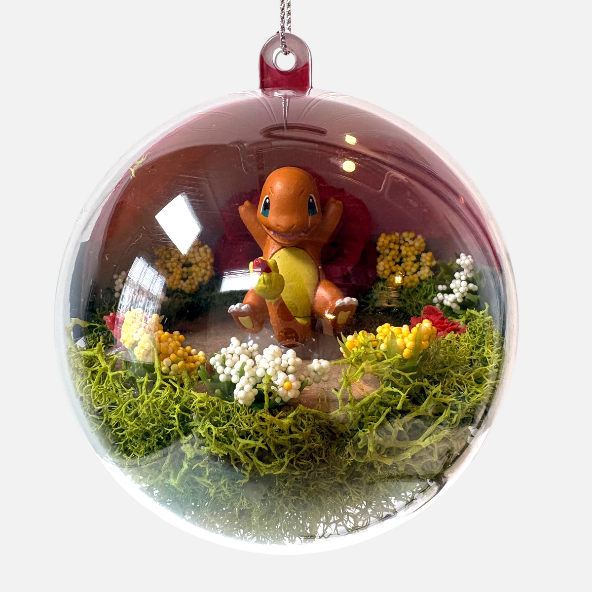Uni-T Pokeball terrarium ornament featuring a Charmander figure inside a clear plastic sphere with moss and flowers