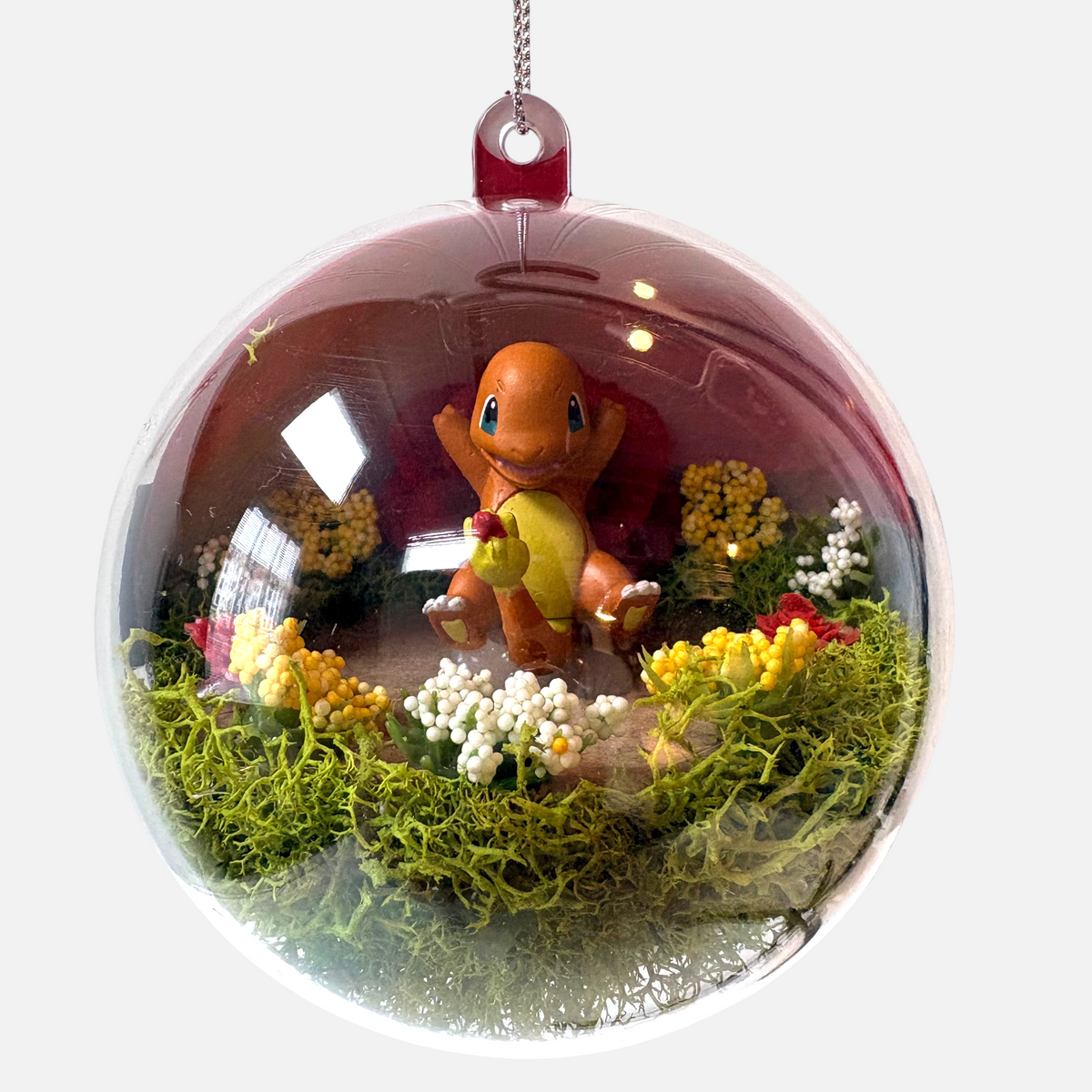 Uni-T Pokeball terrarium ornament featuring a Charmander figure inside a clear plastic sphere with moss and flowers