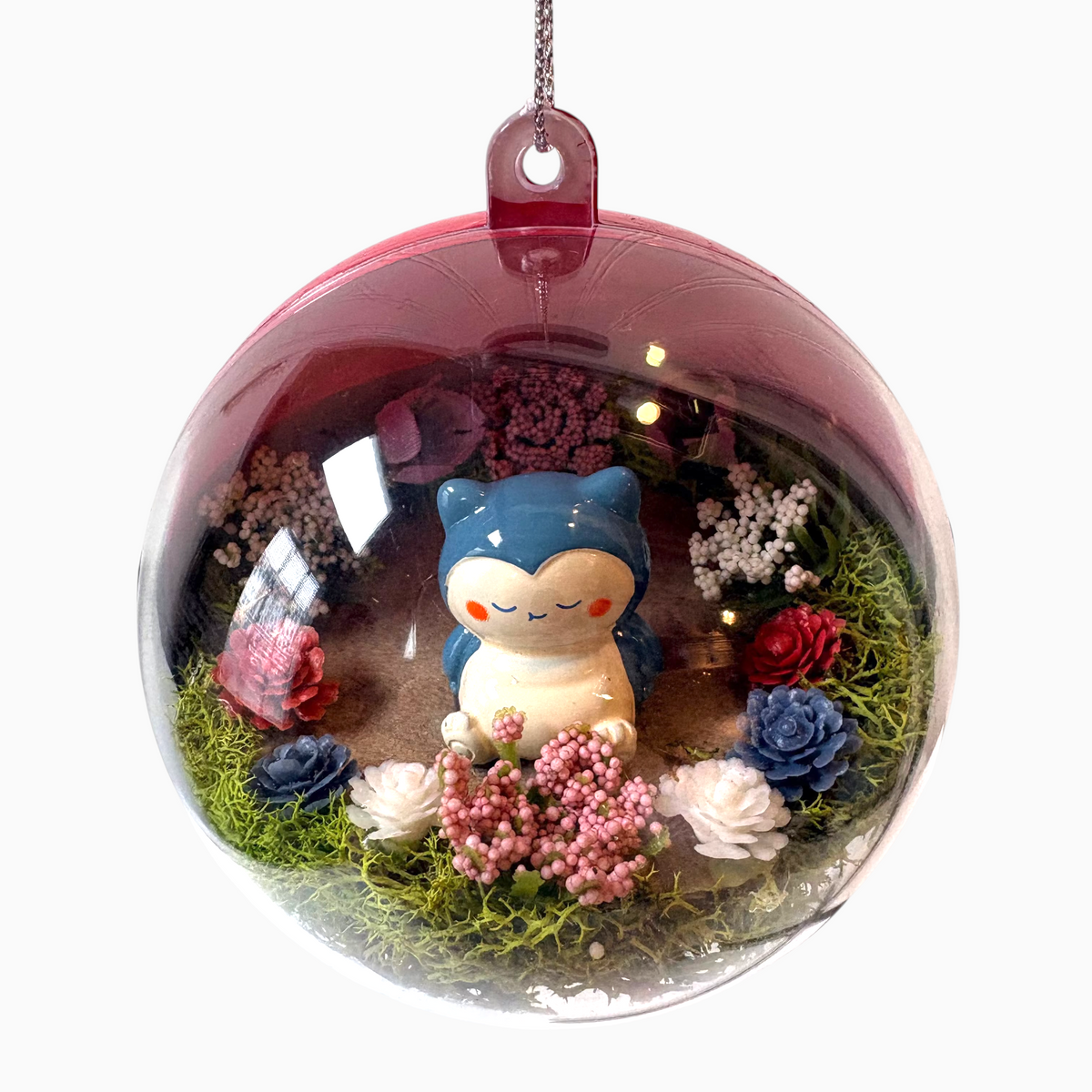 Uni-T Pokeball terrarium ornament featuring a Snorlax figurine surrounded by moss and miniature artificial flowers