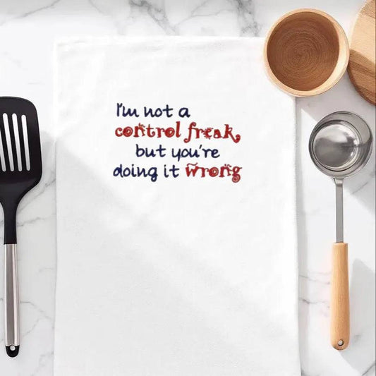 Funny embroidered kitchen towel with red and blue text reading 'I'm not a control freak, but you're doing it wrong' on a marble countertop. Great small gift idea.