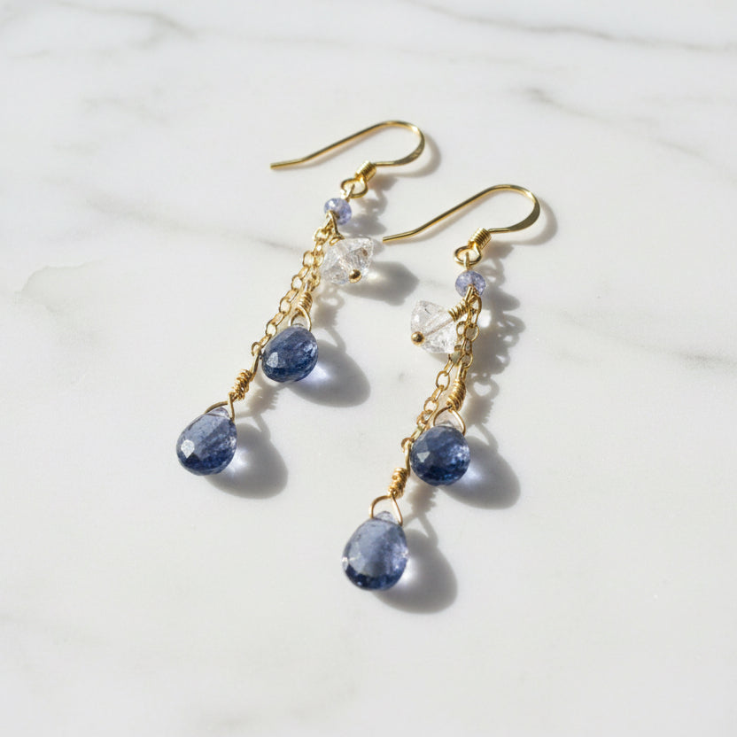Close-up of gold chain drop earrings with blue and clear gemstones