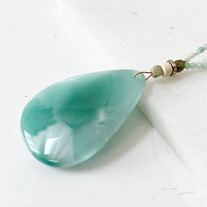 Detailed view of polished dark green moonstone teardrop pendant showing iridescent shine, part of 18-inch necklace with silver clasp.