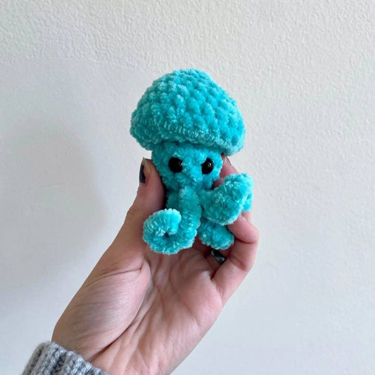 Hand holding a handmade Jellyfish Pop Fidget Toy made of soft turquoise chenille yarn. Ideal small gift for stress relief and sensory play.